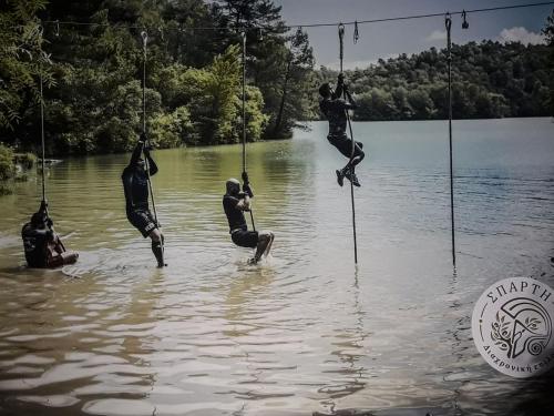 a group of people are in the water on rope swings at HELLAS PALACE ROOMS balcony in Sparti