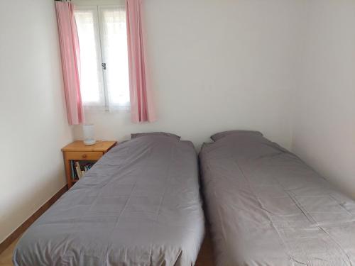 two beds in a small bedroom with a window at Colchique in Le Mas