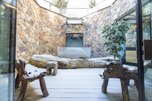 a room with a stone wall with a log and two chairs at Upside Down Town Hotel Neue Post in Zell am See