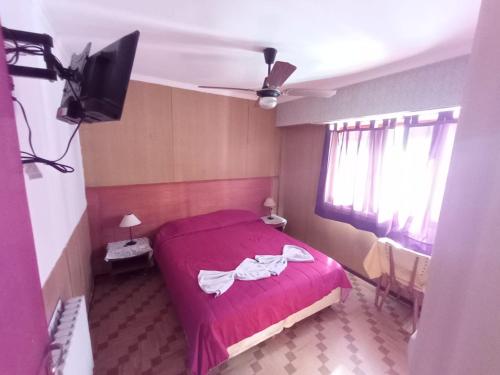 a bedroom with a red bed and a flat screen tv at Nuevo Hotel Tivoli in Mar del Plata