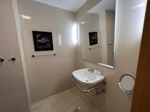 a white bathroom with a sink and a mirror at Quartos no QS Marista in Goiânia