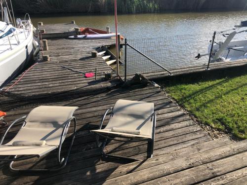 two chairs sitting on a dock next to a boat at 25h GARDEN Apartment PLUS private Beach in Neusiedl am See