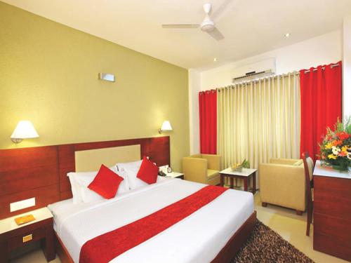 a hotel room with a large bed with red accents at Hotel Hills Park in Pathanāmthitta