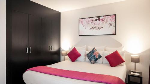 a bedroom with a large white bed with red pillows at Residhome Val d'Europe in Montévrain