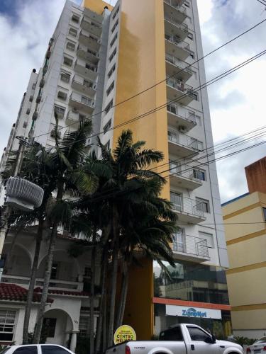 a tall building with palm trees in front of it at Central, próximo ao HCAA e Calçadão in Santa Maria