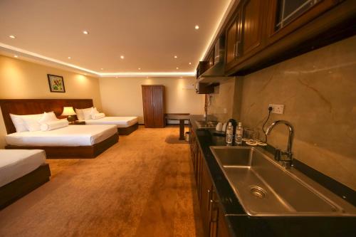 a hotel room with two beds and a kitchen with a sink at Serene Kandy in Kandy