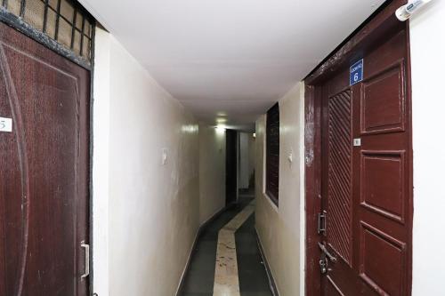 un couloir vide avec deux portes brunes et un couloir dans l'établissement Hotel Kshama, à Jabalpur