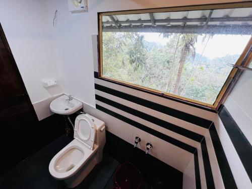 łazienka z toaletą i oknem w obiekcie Raymond's Holiday Homes w mieście Vythiri