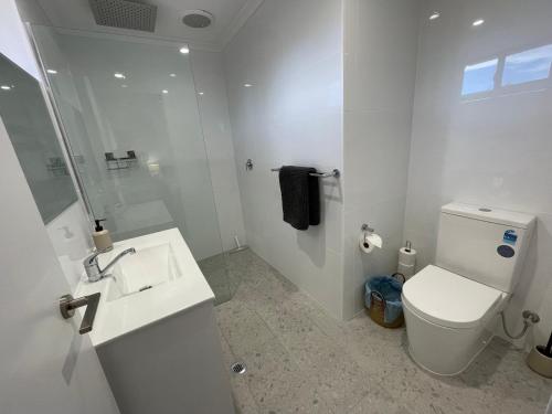 a white bathroom with a toilet and a sink at Carpenter House in Exmouth