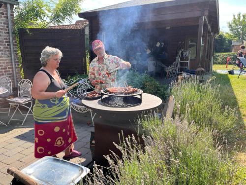 a man and a woman cooking food on a grill at B&B AntiQua & Qook in Tongeren
