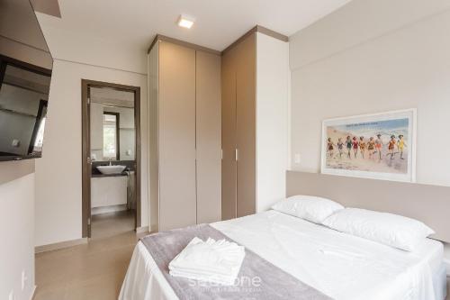 a white bedroom with a bed and a bathroom at Belo apartamento com design moderno ABZ302 in Florianópolis