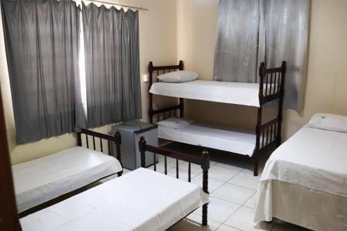 a room with three bunk beds and a window at Hotel Gringos in Londrina