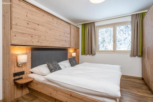een slaapkamer met een groot wit bed en een raam bij Appartements Salitererhof in Saalbach Hinterglemm