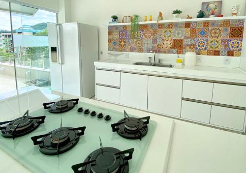 eine weiße Küche mit einem Herd mit Backofen, Töpfen und Pfannen in der Unterkunft Terraço Naturale in Domingos Martins