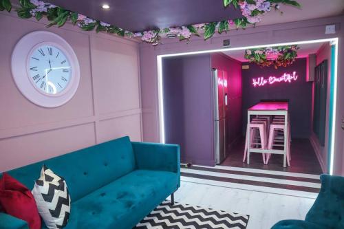 un salon avec un canapé bleu et un réveil dans l'établissement Manchester's ONLY themed slumber party suite for 8 with makeup room, à Manchester