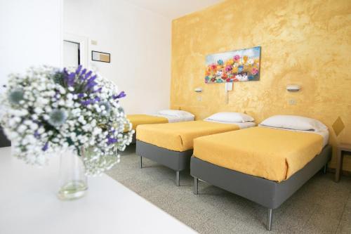 una stanza con tre letti e un vaso di fiori di Hotel Hollywood a Rimini