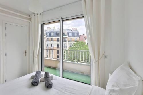 une chambre avec un lit avec une grande fenêtre dans l'établissement Lovely 1 BR Flat with balcony near metro line 10, à Boulogne-Billancourt
