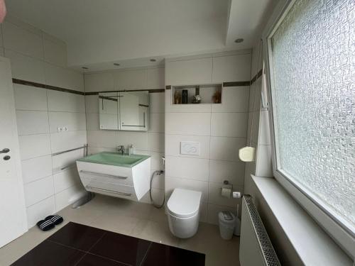 uma casa de banho com um lavatório, um WC e uma janela. em Schickes 110qm Ferienhaus in Nähe VW, DEZ und Orangerie em Kassel