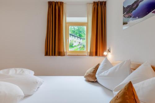 - une chambre avec un lit doté de draps blancs et une fenêtre dans l'établissement Ausserglieshof Wohnung Weißkugel, à Malles Venosta