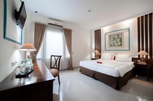 a hotel room with a large bed and a desk at Noola Inn Hotel Bogor in Kamparganya