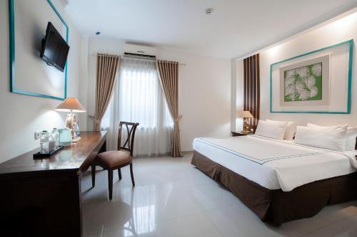 a hotel room with a bed and a desk and a bed and a desk at Noola Inn Hotel Bogor in Kamparganya