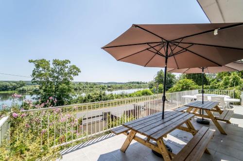 a patio with two benches and an umbrella at Appart Face Loire Blois Terrasse Parking Jardin Jacuzzi Parking Vélos in Blois
