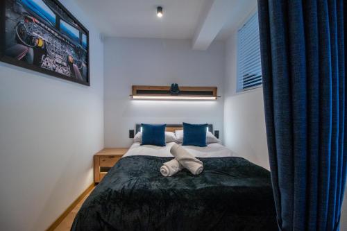 a bedroom with a bed with blue pillows at Apartament AVIATOR - lokalizacja w centrum, wysoki standard z KLIMATYZACJĄ, balkon, prywatny parking in Nowy Targ