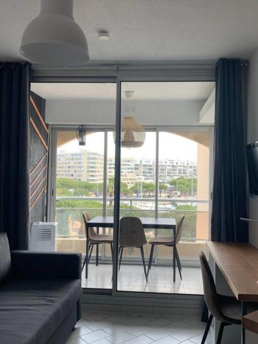 - un salon avec une table, des chaises et une grande fenêtre dans l'établissement Sur port de Carnon / Palavas charmant petit studio, à Mauguio