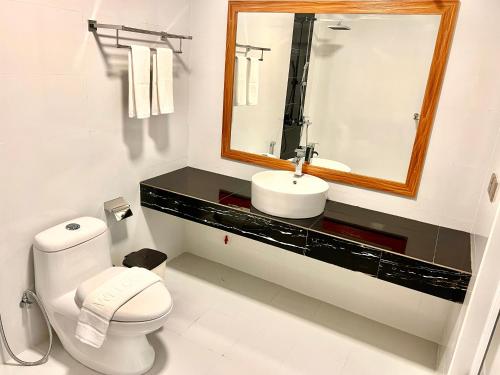 a bathroom with a sink and a toilet and a mirror at Vilu Residence in Maamigili
