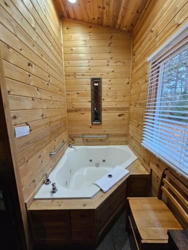 a bathroom with a tub in a wooden wall at Honey Bear Haven Suite 5 in Eureka Springs