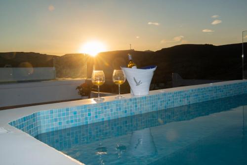 a swimming pool with wine glasses and a bottle of wine at Myrsini's Luxury Suites Merchia in Mýkonos City