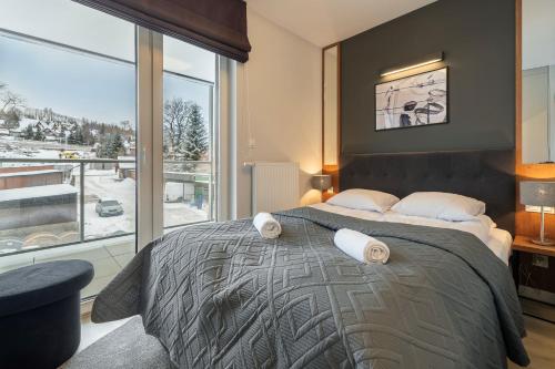 a bedroom with a large bed with a large window at RentPlanet - Apartamenty Zakopiańskie in Zakopane