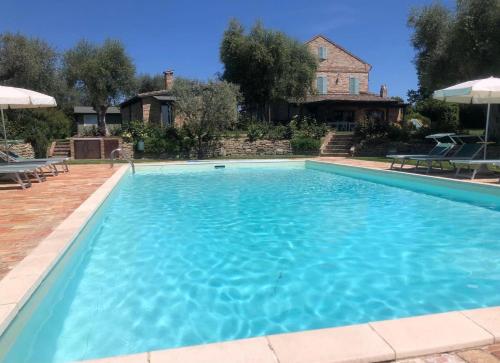 a large blue swimming pool in front of a house at La Villa degli Ulivi in Fermo