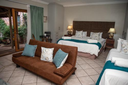 a bedroom with two beds and a couch with pillows at Bluewater Reservations in Port Elizabeth