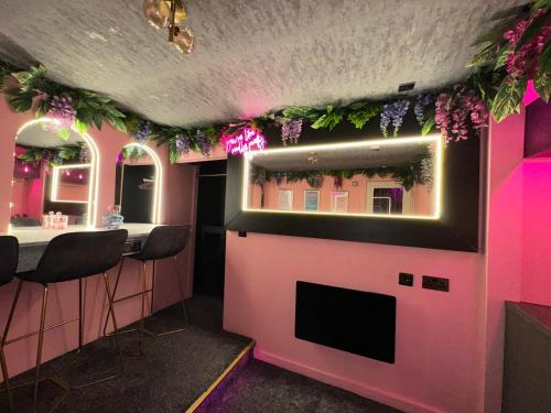 a pink room with a bar with flowers on the wall at The Ultimate Hen Suite with Bar & Makeup Room in Manchester