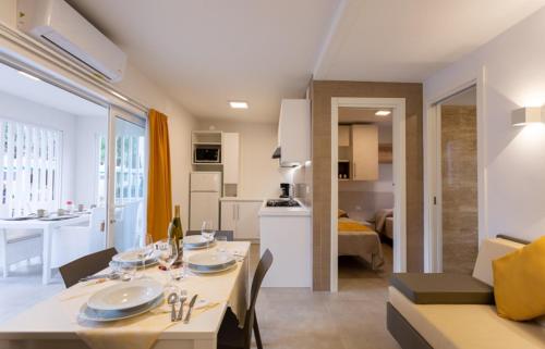 a dining room and living room with a table and a kitchen at Village Camping Joker in Cavallino-Treporti