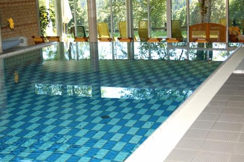 a swimming pool with a blue and white tile floor at Hotel Ramsauhof Pool & Wellness Breakfast & Light Dinner Buffet in Ramsau am Dachstein