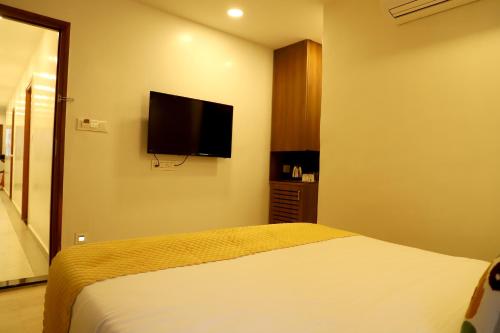 a bedroom with a bed and a flat screen tv at Hotel Hinduja Empire in Surat