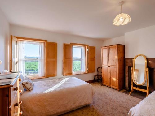 a bedroom with a bed and a mirror and windows at 1 bed property in Allonby 28790 in Allonby