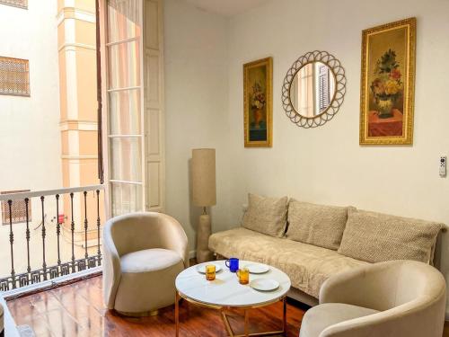 マラガにあるApartamentos Málaga centroのリビングルーム(ソファ、椅子2脚、テーブル付)