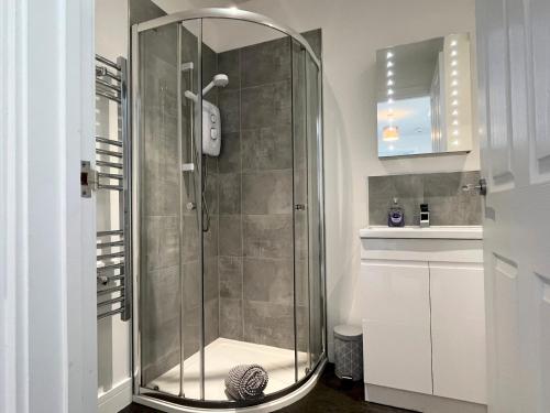 W łazience znajduje się szklana kabina prysznicowa i umywalka. w obiekcie Stunning Town Centre Penthouse w/ Sea Views w mieście Penzance