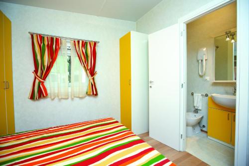 a bedroom with a bed and a bathroom with a sink at Village Camping Joker in Cavallino-Treporti