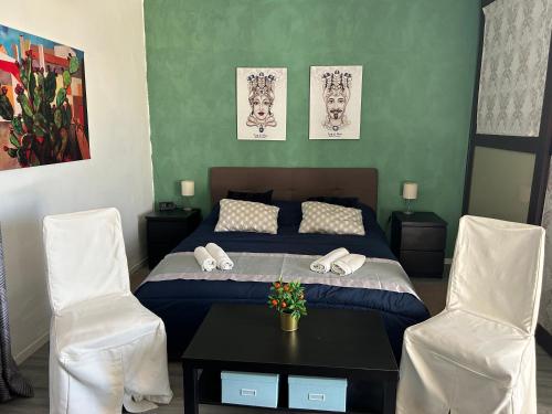 a bedroom with a bed and two white chairs at Residenza Parco Gioeni in Catania