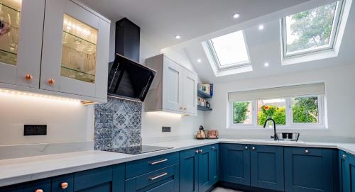 - une cuisine avec des placards bleus, un évier et des fenêtres dans l'établissement Exquisite renovation in central location, à Hereford