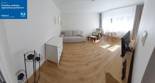 sala de estar con sofá blanco y suelo de madera en Przytulny, spokojny, wyposażony apartament, en Poznan