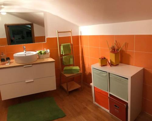 an orange bathroom with a sink and a mirror at B&B A Modo Mio in Bologna