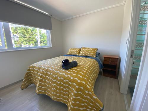 1 dormitorio con 1 cama con manta amarilla en Cómodo depto cerca de balneareo, en Llanquihue