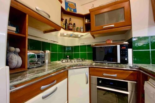 - une cuisine avec du carrelage vert sur le mur dans l'établissement The elegant- 2 bedrooms and central!, à Montpellier