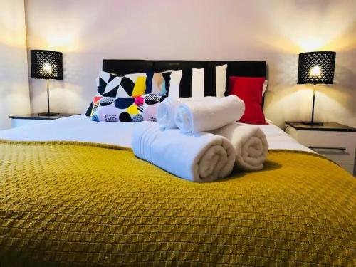 een groot bed met handdoeken en kussens erop bij Lux Home Stays - Regents Place in Leamington Spa