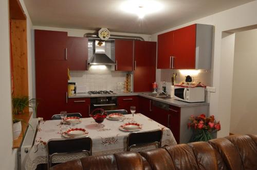 une cuisine avec des placards rouges et une table avec des chaises dans l'établissement Appartement Timgad, à Gérardmer